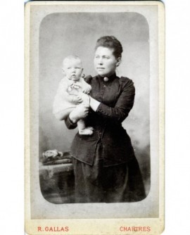 Femme en robe noire debout, un bébé dans les bras