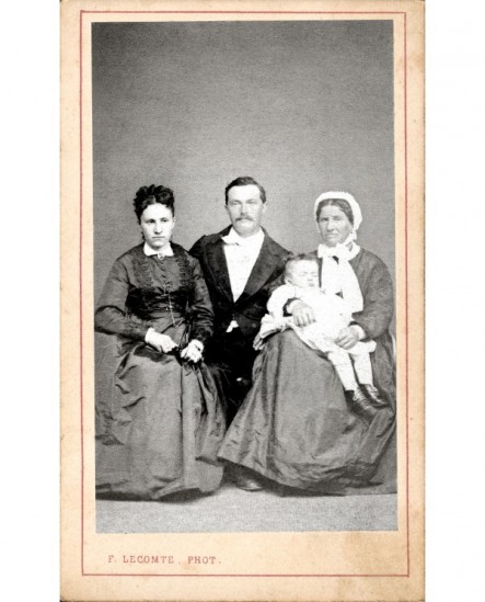Famille: parents endimanchés et grand-mère en coiffe tenant un garçonnet