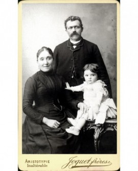 Photo de famille : père moustachu debout, femme assise et enfant