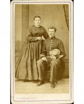 Couple: militaire assis, képi à la main, et femme debout