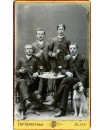 Quatre hommes attablés avec deux chiens