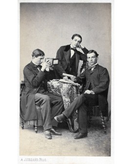Trois jeunes hommes en costumes regardant dans un stéréoscope
