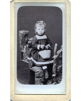 Fillette debout tenant un panier (jouet). Germaine Bouché