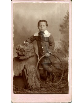 Enfant debout avec veste à col de dentelles tenant un cerceau