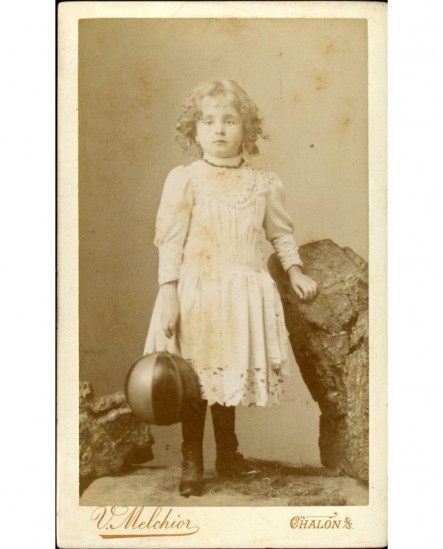 Petite fille en robe blanche debout tenant un ballon