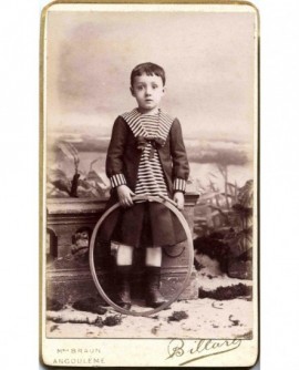 Garçon debout en robe de marin tenant baguette et cerceau (jouet)